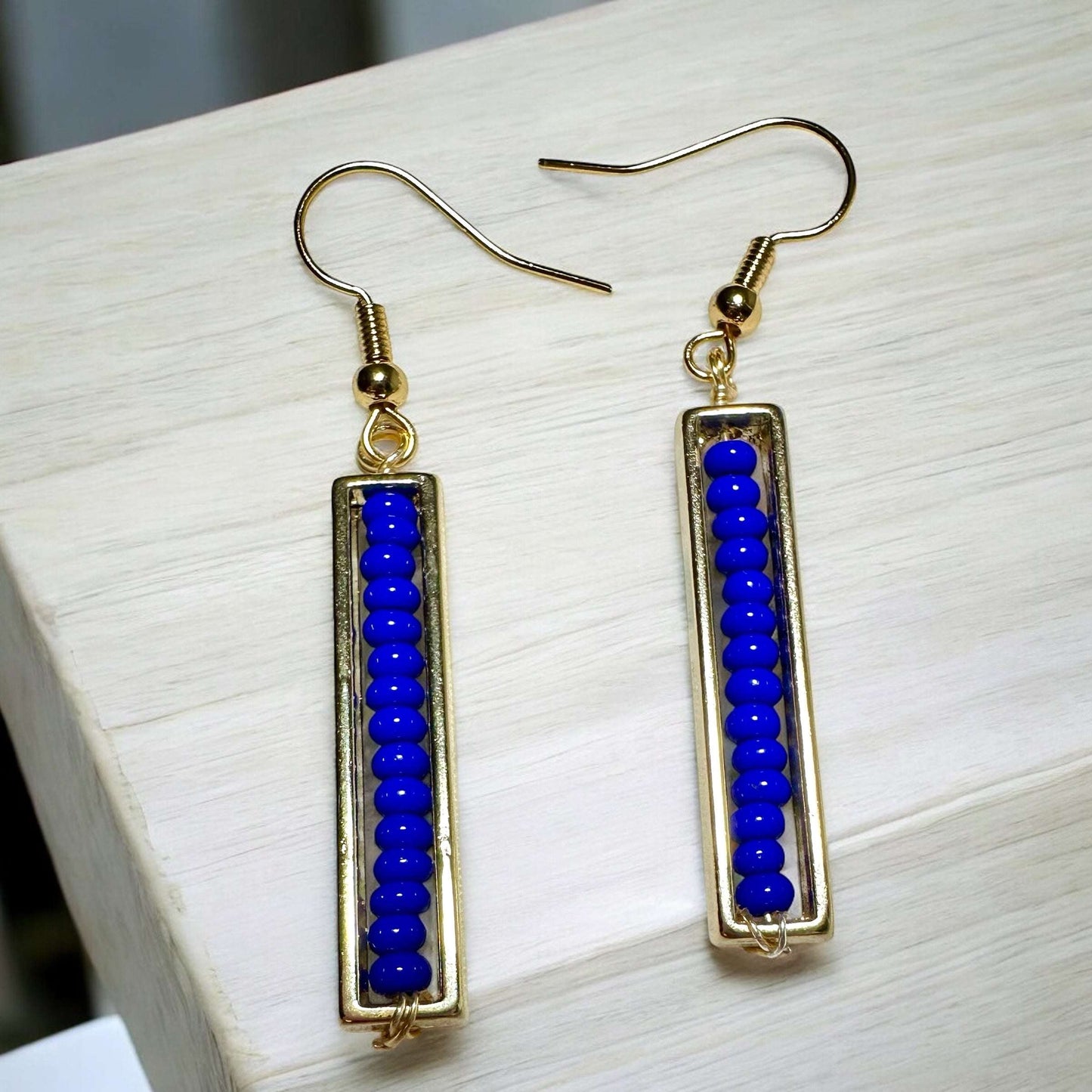 Spectrum strips beaded earrings gold plated ear wire earrings in blue on table