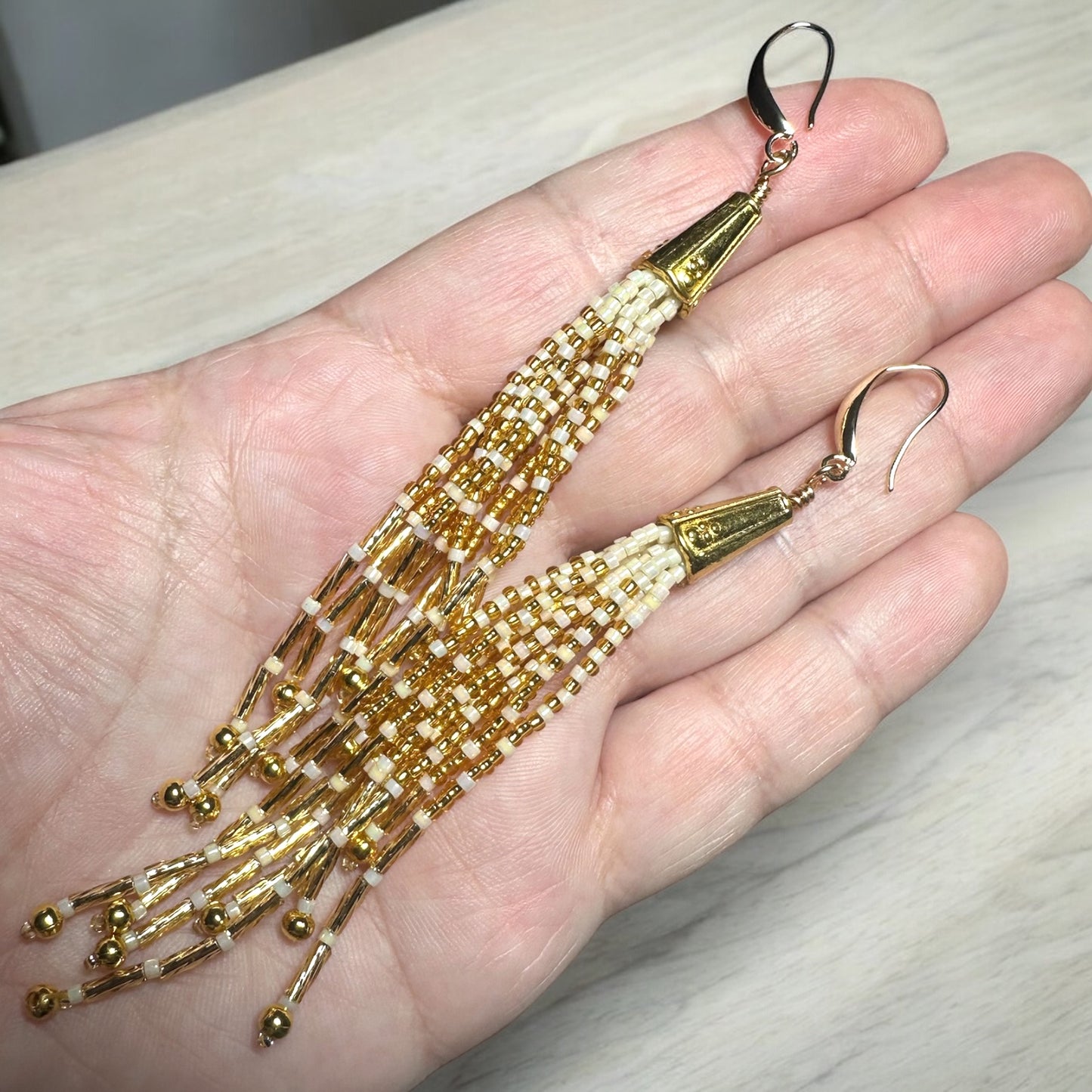 Tassel earrings with gold filled ear hook in gold and cream colors. In hand for scale