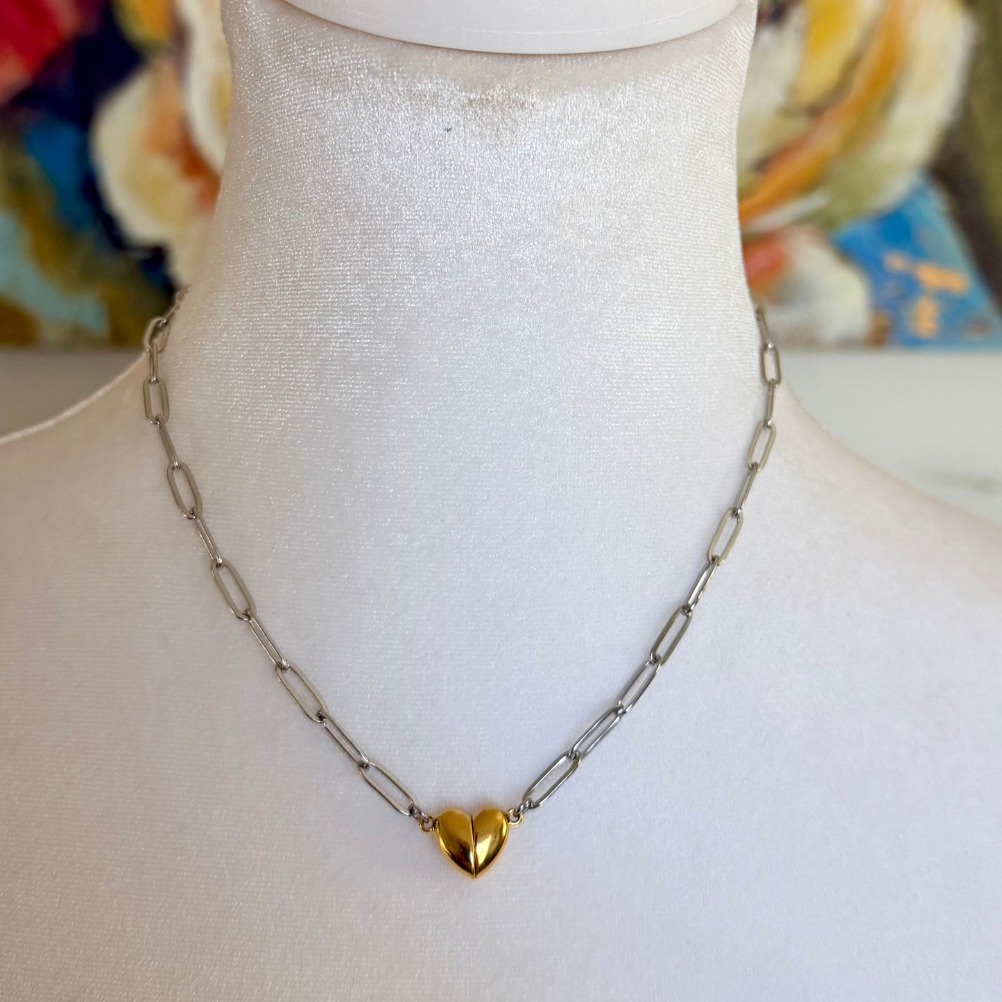 Necklace with a heart pendant on a mannequin bust against a colorful abstract background