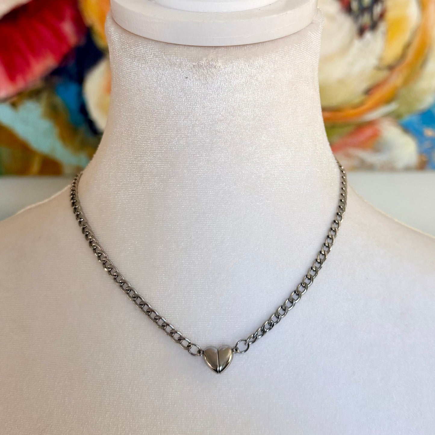 Necklace with a heart pendant on a mannequin against a colorful abstract background