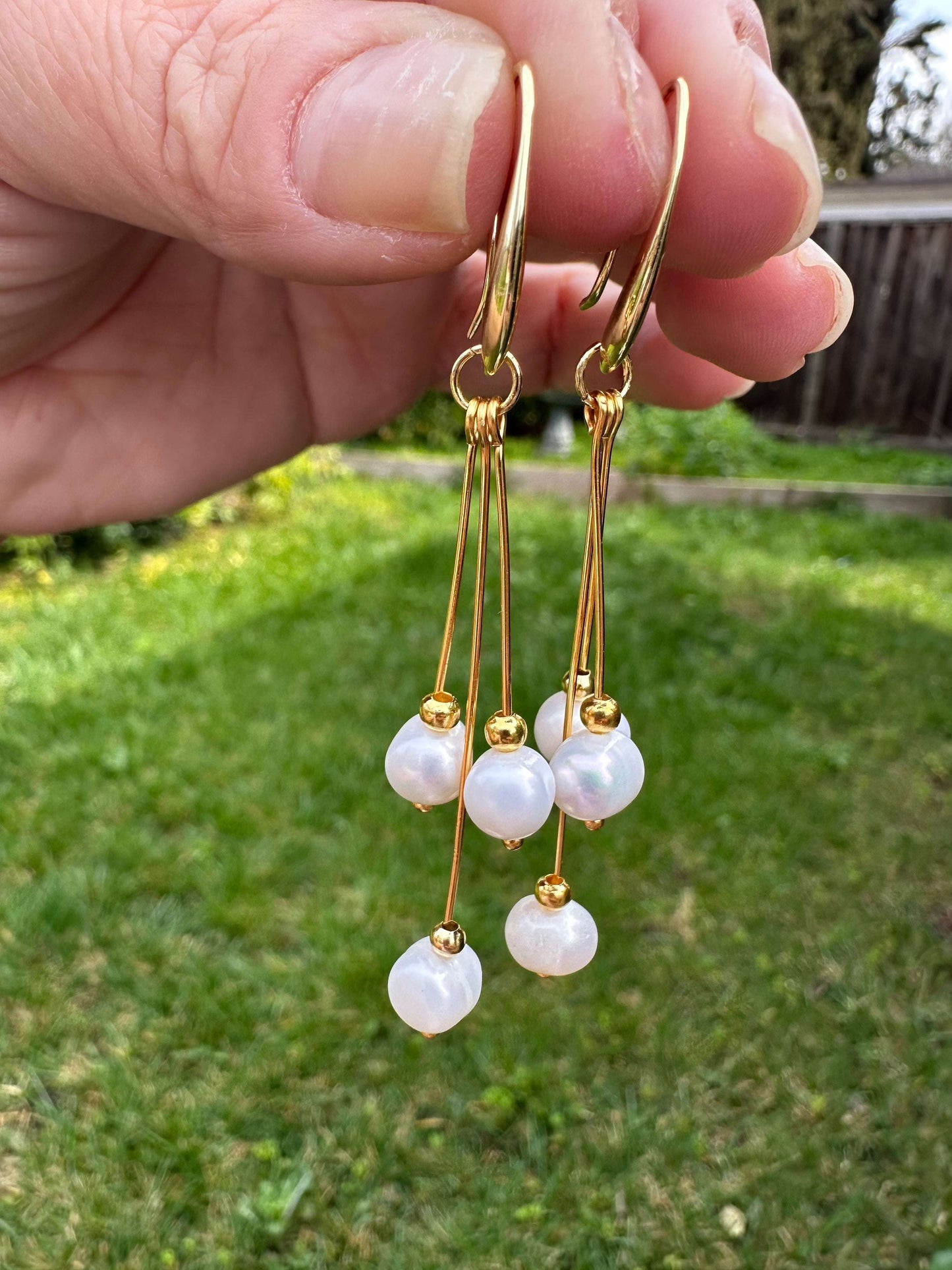 Pure Elegance Earrings - Gold Filled with pearls hanging from fingers