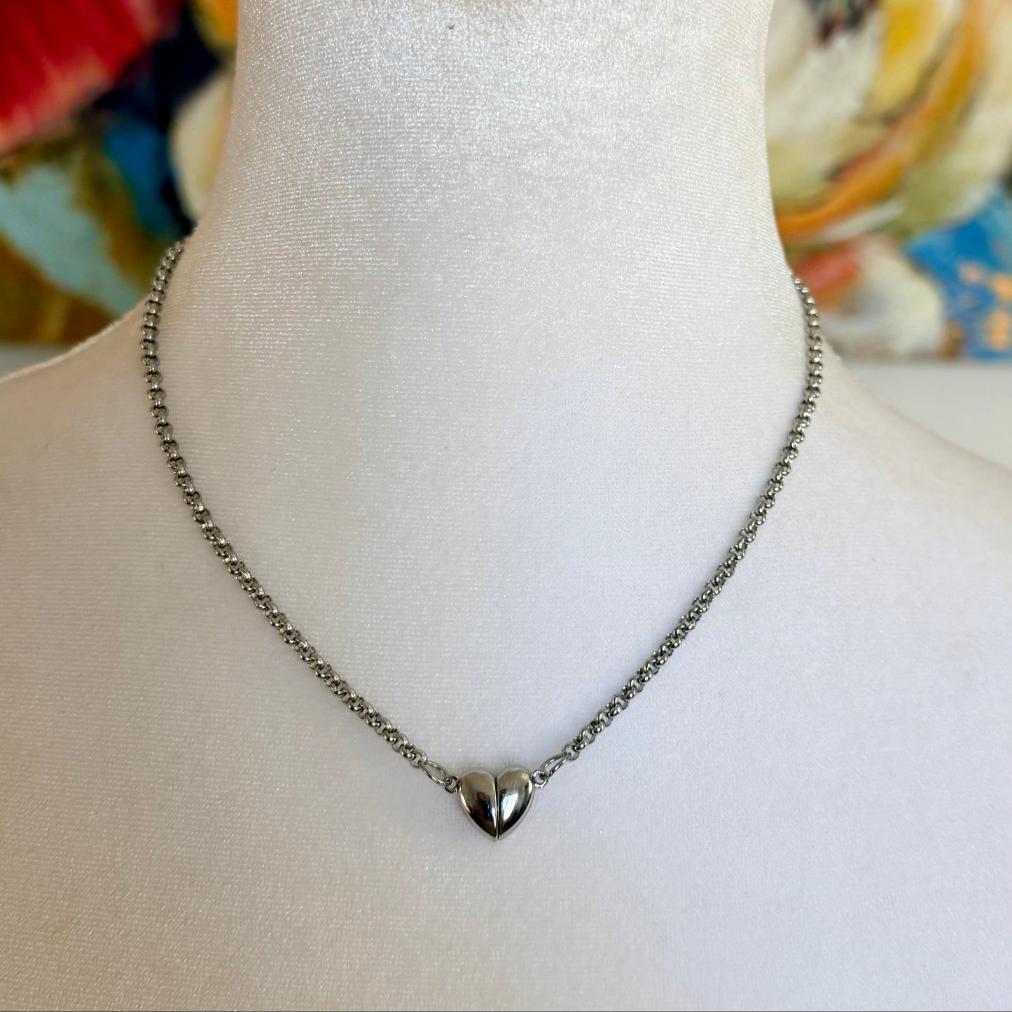 Necklace with a heart pendant on a mannequin bust against a colorful abstract background