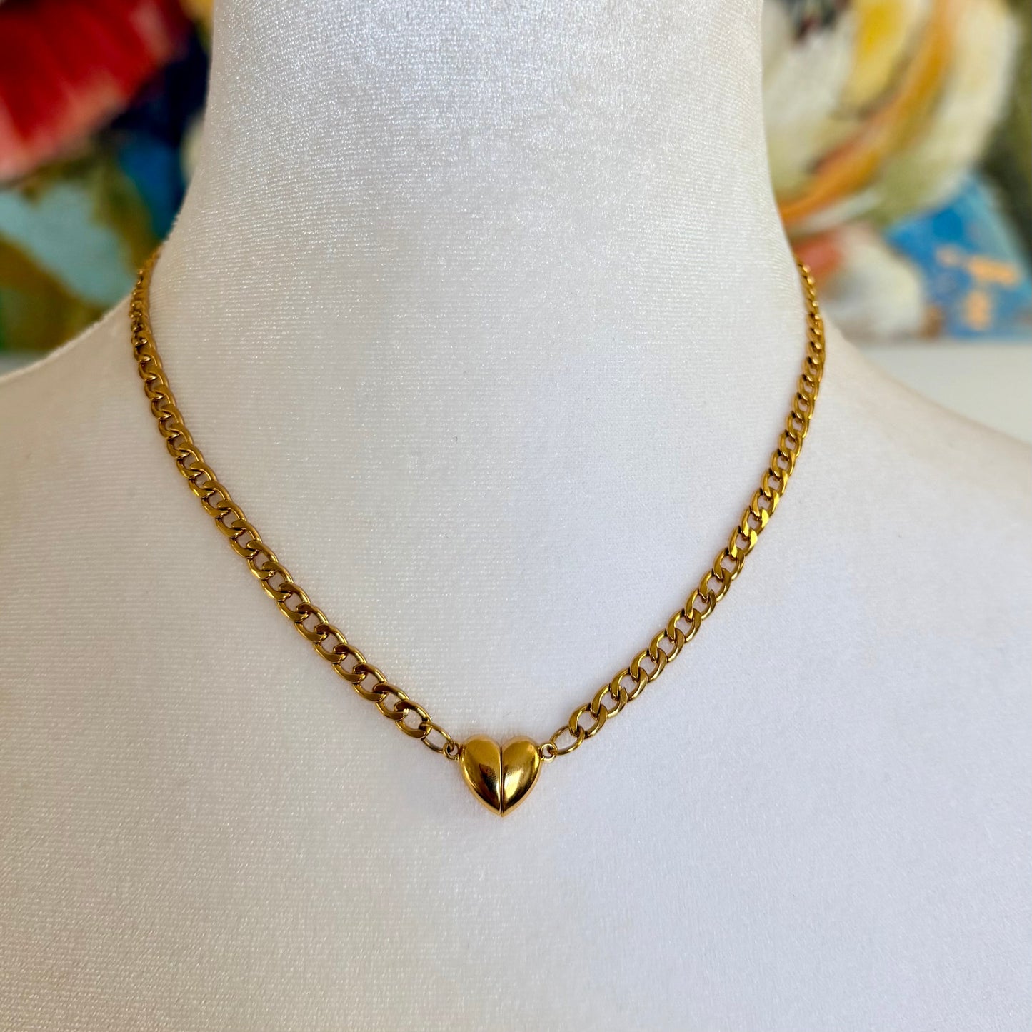 Gold chain necklace with a heart pendant on a mannequin bust.